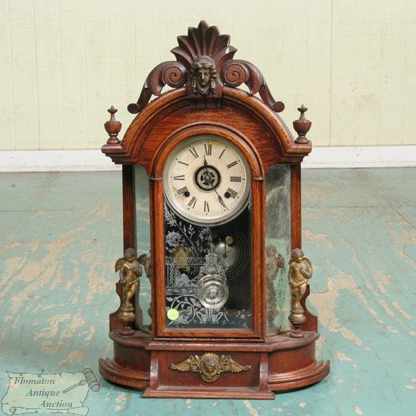 Late 19th Century mirror side wall clock, Ansonia,: Late 19th Century mirror side wall clock, Ansonia, solid oak, Triumph model, reticulated scrolled leaf and shell crest, metal Jenny Lind head and statues on sides, 24 1/2"t, 16 1/2"w, 6"d. Original cr