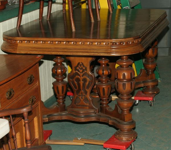 1930 Art Deco period dining table, carved and mol: 1930 Art Deco period dining table, carved and molded skirt, walnut top, four large bulbous turned double pedestal ends, flat molded stretcher with finial, 42"w 61"l , one 12" self storing leaf. Good c