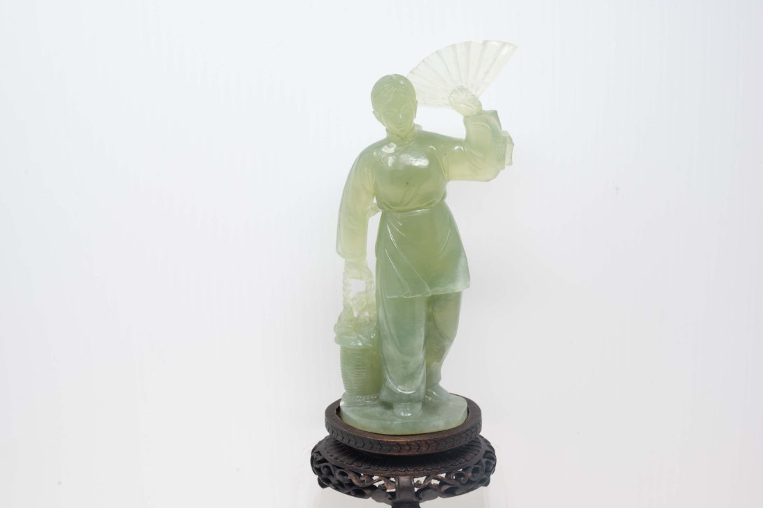 Chinese Light Green jade Carving of Lady with Basket & Fan: Chinese light green jade carving of a young lady with a basket and a fan on a wooden base. The sculpture only measures 7 1/4 inches tall. Apart from the chip shown in the photo, comes in good conditio