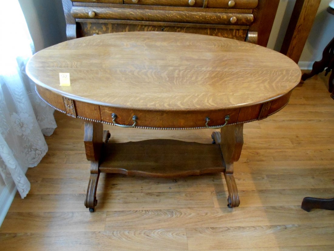 Antique American Oval Oak Sofa Table – Furniture: Large antique American oval sofa/lamp table. Cross sawn tiger oak. Beaded accent carving, and carved legs. Shelf stretcher. Finish very clean (refinished?). 2 drawers Metal pulls. Metal casters on fee