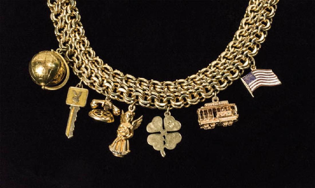 14K GOLD CHARM BRACELET Bracelet with seven charms:: 14K GOLD CHARM BRACELET Bracelet with seven charms: globe, "Playboy Bunny" key, dial telephone, angel "June", four-leaf clover "13", San Francisco trolley car "Powell & Hyde", and American flag, 7 3/4