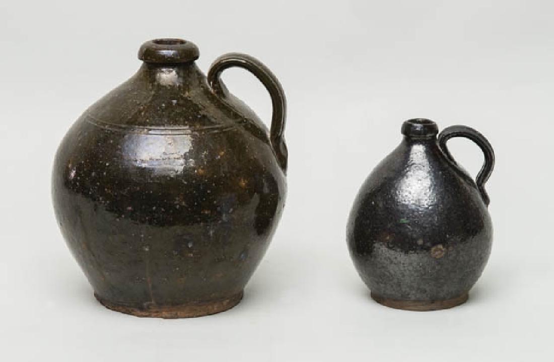 TWO 19TH C. OVOID REDWARE JUGS Larger jug with heavy: TWO 19TH C. OVOID REDWARE JUGS Larger jug with heavy lip, brown/green glaze with orange spots, double incised line at neck, 9 1/2" h; Smaller jug with dark brown glaze, overall good condition, 7 1/2"