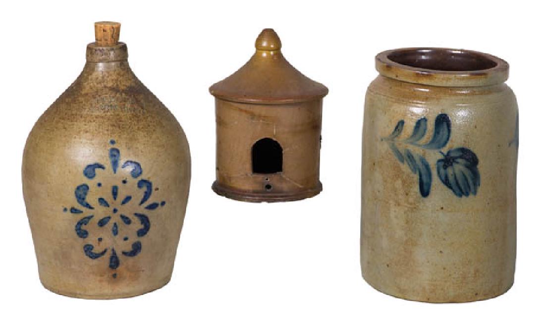 THREE STONEWARE PIECES Straight sided crock with tulip: THREE STONEWARE PIECES Straight sided crock with tulip decoration, (age lines), 10" h; Two-gallon jug with stenciled blue flower, marked "H. Cowden, Harrisburg"; Bird house, (repaired), in a light bro
