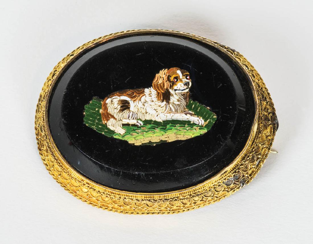 VICTORIAN MICRO-MOSAIC PIN: VICTORIAN MICRO-MOSAIC PIN Oval pin with 10K gold edged tracery, depicting on a raised jet black background a King Charles spaniel on a green pillow, (minor wear to top, some repairs to gold edge), 2"