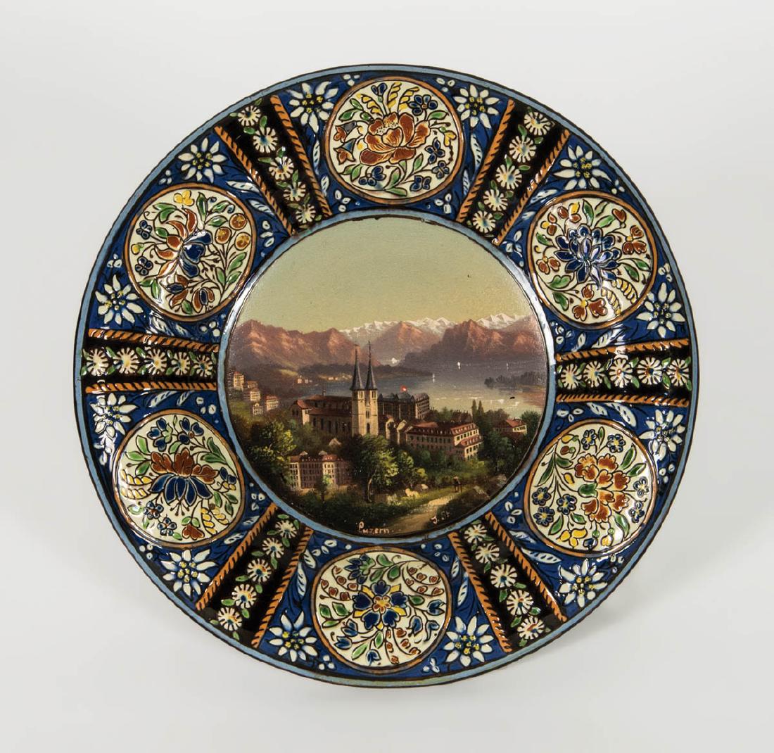 MAJOLICA PLATE: MAJOLICA PLATE Central hand-painted scene of Luzern, Switzerland, with cathedral castle and view of the lake, six hand-painted round floral decorations on rim, artist signed "J. St.", and on the back 