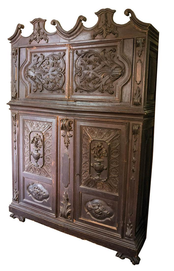 EARLY 18TH C. EUROPEAN ARMOIREHeavily carved walnut,: EARLY 18TH C. EUROPEAN ARMOIREHeavily carved walnut, with fold down hinged lid, writing surface with ornate applied carvings, over a double door cupboard space, panel doors with carved raised pots of 