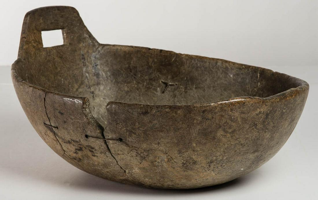 EARLY 18TH C. NATIVE AMERICAN BURL BOWLOval shape with: EARLY 18TH C. NATIVE AMERICAN BURL BOWLOval shape with single raised carved handle at one end, original surface with patina, old copper wired repairs to three splits, 8" h (to top of handle), 5 1/2" h