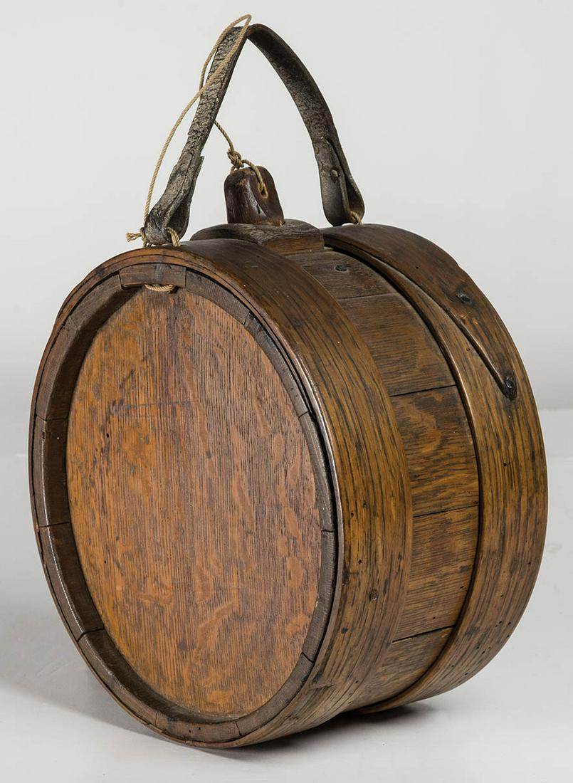 18TH C. FIELD CANTEENOak, rosehead nailed and wood: 18TH C. FIELD CANTEENOak, rosehead nailed and wood pegged wraps, maple plug and leather strap appear to be early replacements, 9 3/4" dia, 5 3/4" w.