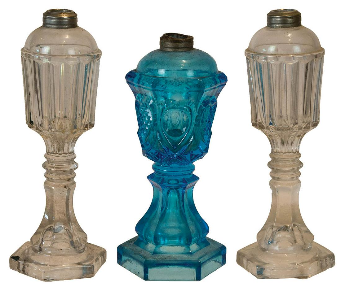 THREE 19TH C. OIL LAMPSPressed glass oil lamps, two: THREE 19TH C. OIL LAMPSPressed glass oil lamps, two matching clear fonts, 10 1/2" h, and a blue oil lamp with hearts and diamonds, 10" h.