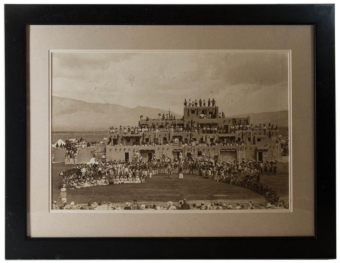 LARGE PHOTOGRAPH OF PUEBLO VILLAGE"The Painted Desert",: LARGE PHOTOGRAPH OF PUEBLO VILLAGE"The Painted Desert", showing a large ceremony with Native Americans in full dress, with eagle feather bonnets, musicians, children, and onlookers in front, framed an