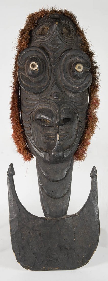 NEW GUINEA HANGING RACKHanging rack, large carved: NEW GUINEA HANGING RACKHanging rack, large carved facial features, shell eyes, original black finish, trimmed in raffia, 35" h.