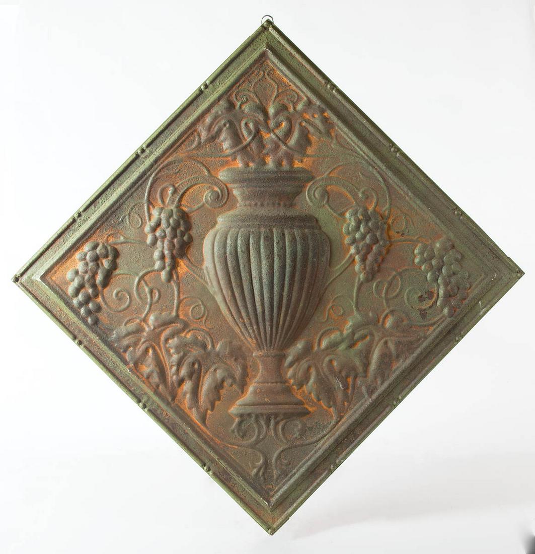 EARLY TIN WOOD FRAMED PLAQUEWall plaque of a repousse: EARLY TIN WOOD FRAMED PLAQUEWall plaque of a repousse urn and bunches of grapes, rust green with orange background, 24 1/2" sq.