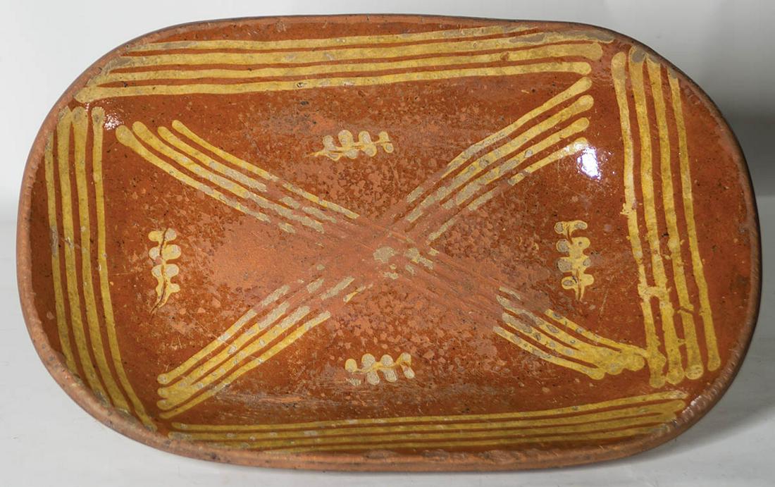 VERY EARLY REDWARE LOAF PANPennsylvania, oval shape,: VERY EARLY REDWARE LOAF PANPennsylvania, oval shape, bold framed yellow line decoration, with interior squiggled leaves, shows "in-use" wear at bottom of interior, 18" l, 12" w.