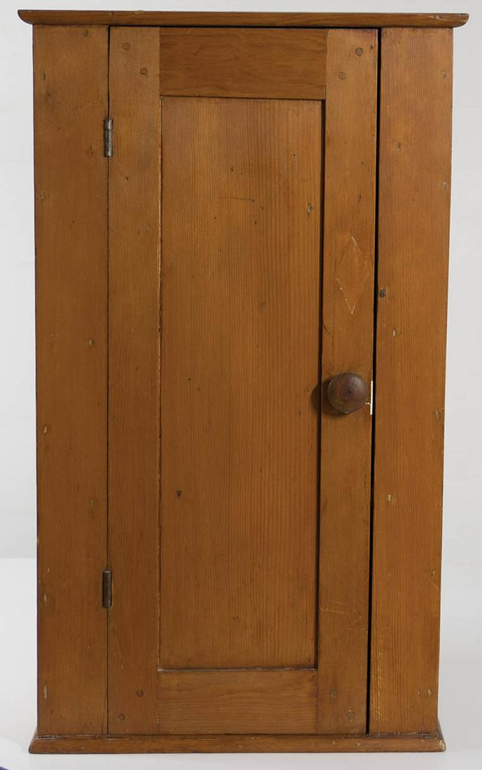 HANGING CUPBOARDPine, traces of original red stain, inset panel door, through mortised and double: HANGING CUPBOARDPine, traces of original red stain, inset panel door, through mortised and double pinned frame on the diagonal, half round molded top board, plank sides, half round molding applied at 
