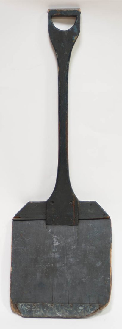 SNOW SHOVEL: Pine, original blue painted finish, shaped handle extending and attached with counter sunk screws to the flat shovel surface, nailed tin reinforced front edge, 41 1/2" l, 13 3/4" w.