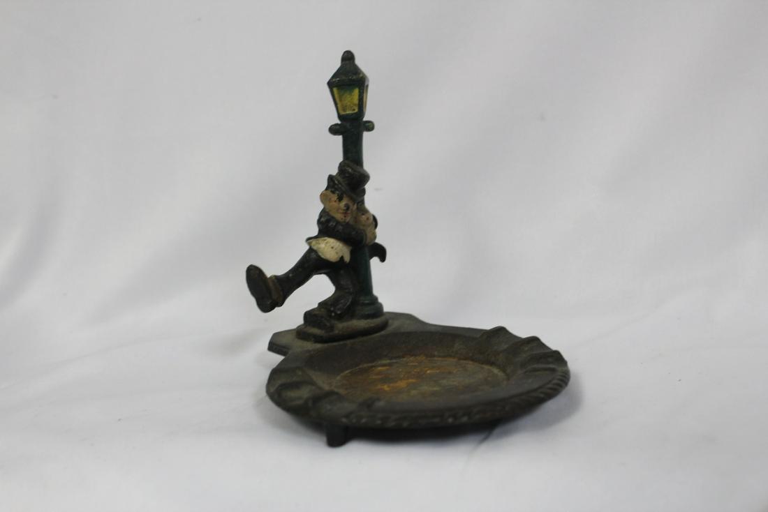 A Vintage Cast Iron Ashtray: with drunk guy hanging on a lamp post - 5" tall