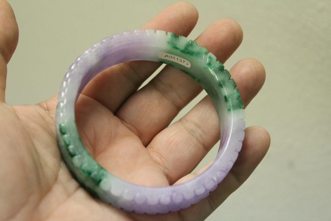 A Carved Jadeite Bangle Bracelet: bicolor - inside diameter= 2 1/4"