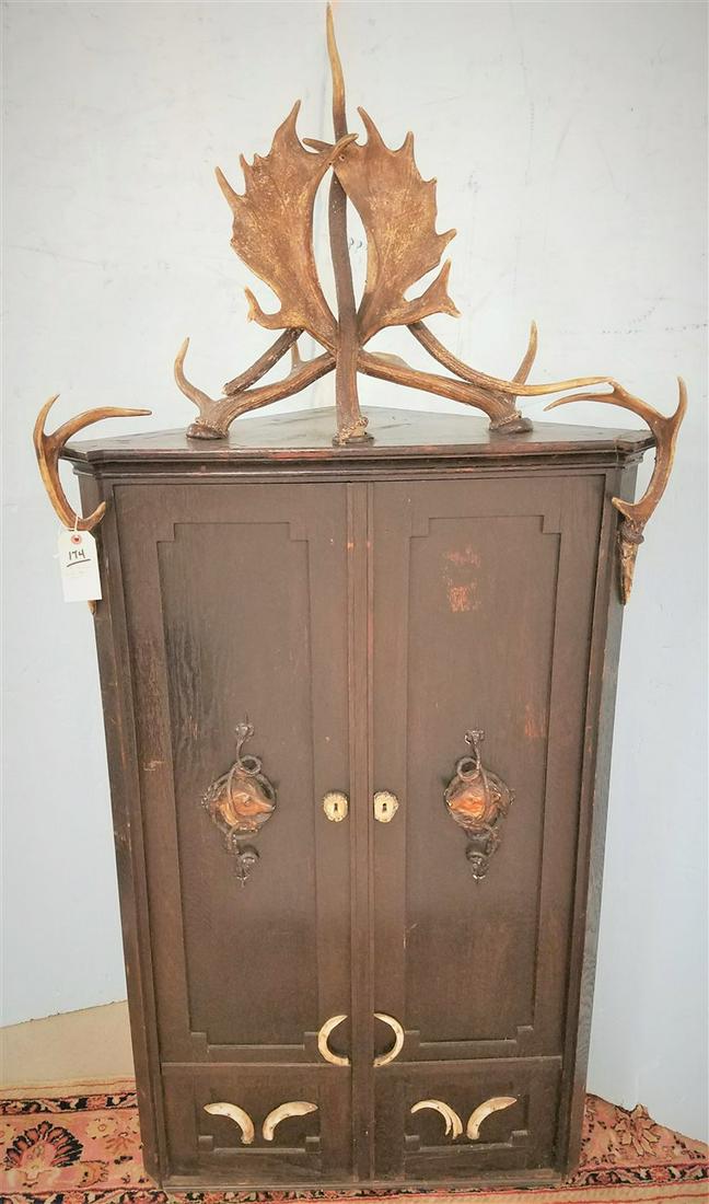 19 TH C. GERMAN OAK 2 DOOR HANGING CORNER GUN CABINET: 19 TH C. GERMAN OAK 2 DOOR HANGING CORNER GUN CABINET W/ANTLERS& BOAR'S TEETH DECORATION 70.5"H X32"W