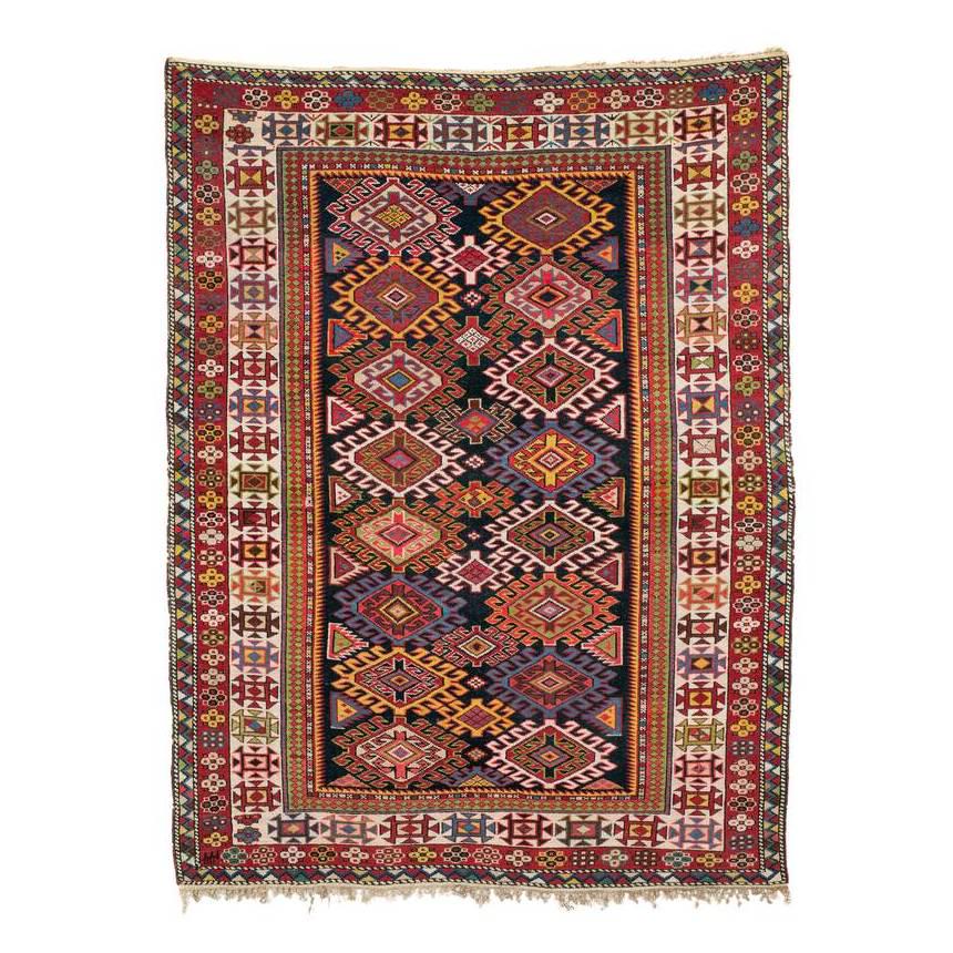 Shirvan: Early 20th century, 154 x 118 cm, East Caucasus A repeat composed of two rows of polychrome hooked diamonds on a midnight blue ground; a white border of squares decorated with triangles. – Good cond