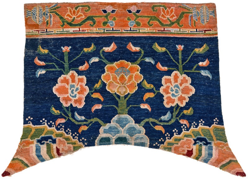 Gyantse Horse Cover: ca. 1900, 104 x 143 cm, Central Asia, South Tibet A horse cover with an arc-shaped lower end and long points. In the dark blue field, three green stems bearing a large peony blossom and small sickle