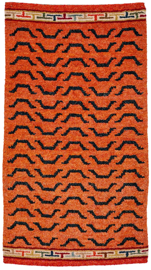 Tiger Stripe Rug: early 20th century, 84 x 48 cm, Central Asia, South Tibet, Gyantse A rare rug woven without any lateral borders. Its orange field shows a design of brown, stylised, trapezoid tiger stripes which