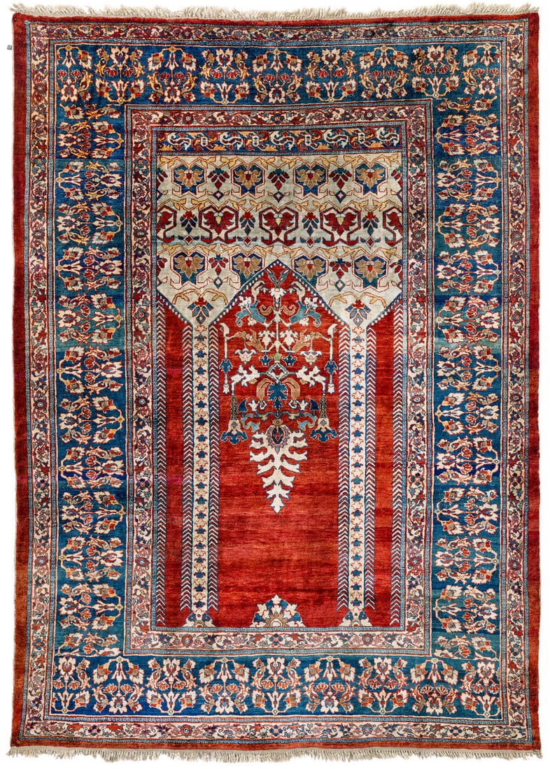 Heriz Silk Rug: second half 19th century, 180 x 134 cm, North West Persia A precious red-ground silk rug woven in a prayer design. Two columns support an arcade of three pointed arches. A large floral feature is