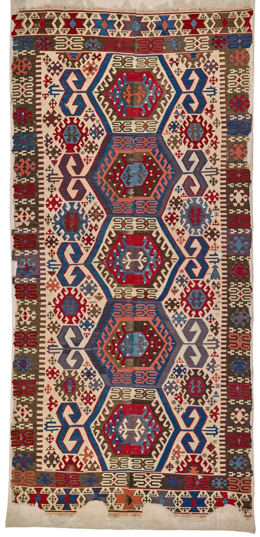 Aydinli Kilim: first half 19th century, 386 x 180 cm, West Anatolia A two-panel kilim with five large hooked hexagons aligned on the central axis of the white field. The motifs are surrounded by wide blue or