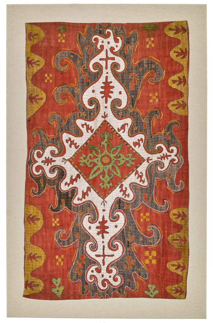 Kaitag Embroidery: ca. 1800 or earlier, 97 x 57 cm, North East Caucasus, Daghestan An elongated white-ground shield form extends across the full length of the orange field. Its wide light brown surround is decorated