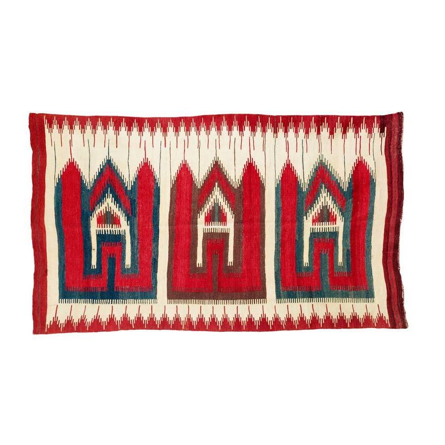 Karapinar Kilim Saf: Late 19th century, 201 x 12 cm, Central Anatolia, Konya region Three large house-like forms, each with a roof shaped into three pointed gables, are aligned horizontally in the white field. The parmakl