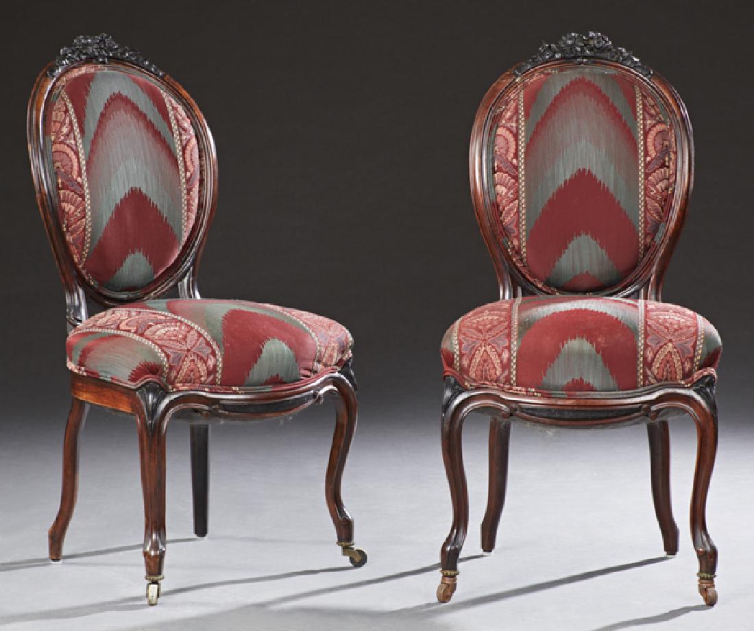 Pair of American Carved Rosewood Rococo Parlor Cha: Pair of American Carved Rosewood Rococo Parlor Chairs, 19th c., with floral carved crest rails over medallion backs, to bowed seats, on cabriole legs with front casters, newly upholstered in flame and