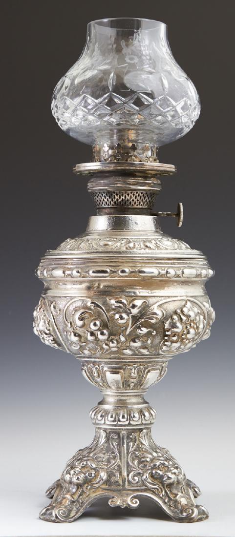 Dutch Silvered Spelter Oil Lamp, late 19th c., by J.J.: Dutch Silvered Spelter Oil Lamp, late 19th c., by J.J. Verburg, with a glass font on a relief base, with a cut and etched glass shade, not electrified. H.- 16 1/4 in., Dia.- 6 in.