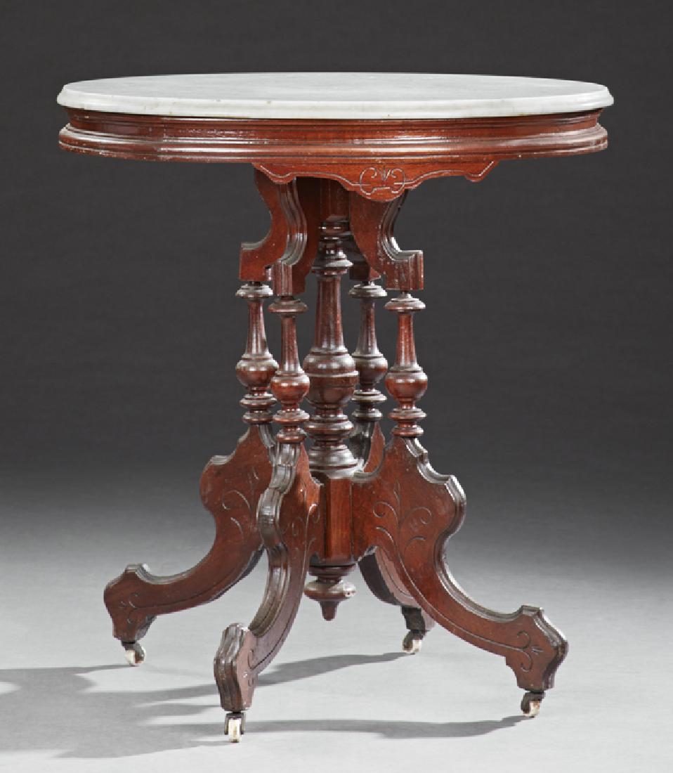 American Eastlake Carved Walnut Marble Top Lamp Table,: American Eastlake Carved Walnut Marble Top Lamp Table, 19th c., the oval ogee edge white marble over a stepped skirt, on four incised flat cabriole legs around a turned center support, on casters, H.-