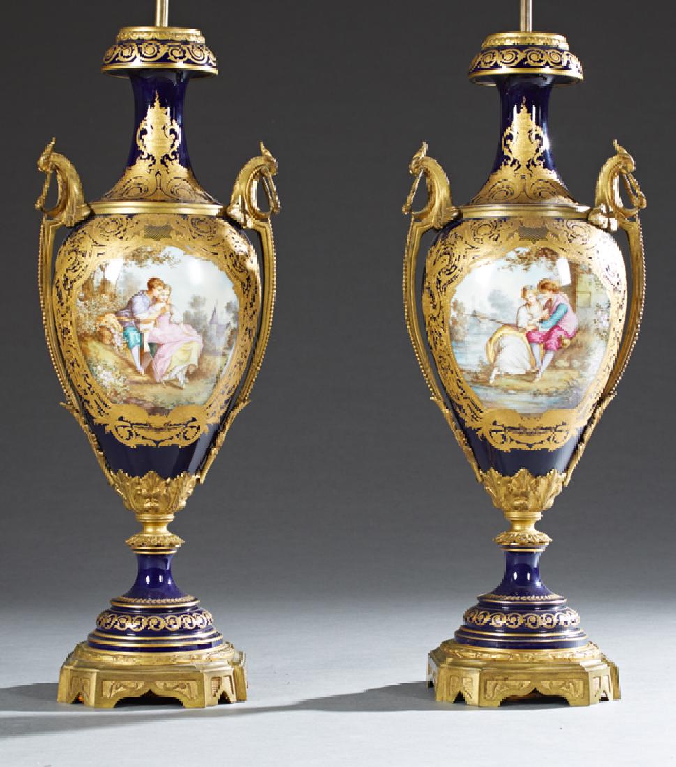 Exceptional Pair of Bronze Ormolu Mounted Cobalt Sevres: Exceptional Pair of Bronze Ormolu Mounted Cobalt Sevres Porcelain Vases, early 20th c., the sides with gilt bronze ring handles and elaborate applied gilt decoration around reserves of lovers in a gar