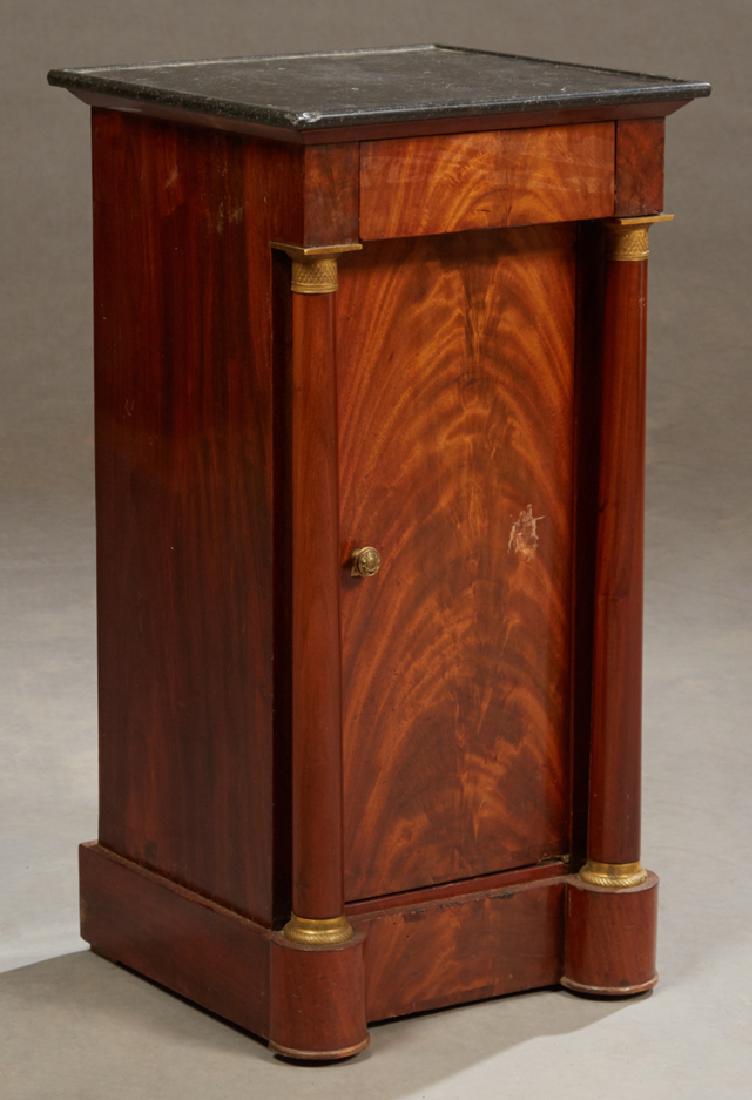 French Empire Style Ormolu Mounted Carved Mahogany: French Empire Style Ormolu Mounted Carved Mahogany Marble Top Nightstand, c. 1820, the dished black marble over a frieze drawer above a setback cupboard door enclosing a shelved interior, flanked by o