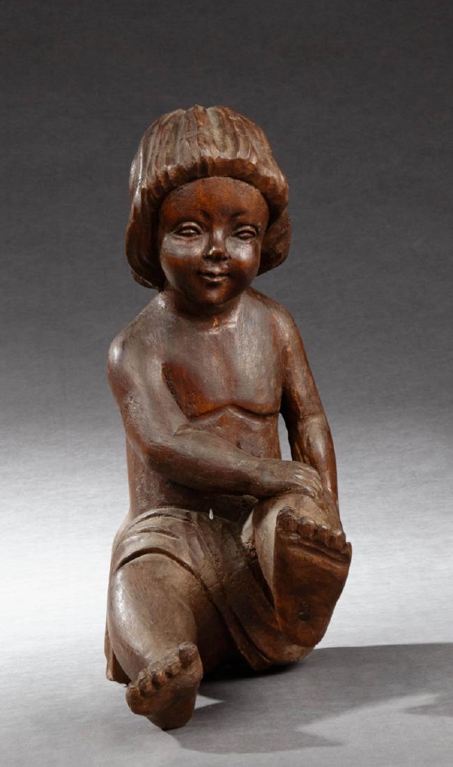 Continental Carved Mahogany Figure, 19th c., of a: Continental Carved Mahogany Figure, 19th c., of a seated child, H.- 15 in., W.- 6 in., D.- 11 in.