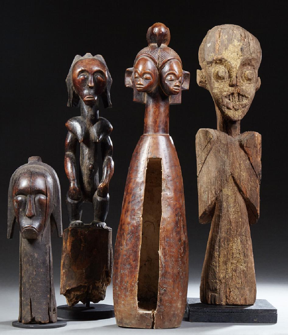 Group of Four African Carved Wooden Figures, consisting: Group of Four African Carved Wooden Figures, consisting of a slit drum topped with female heads; a large male figure with wings on an ebonized wood base; a frowning male figure, Fang tribe, on a steel