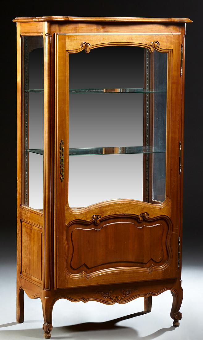 French Louis XV Style Carved Cherry Vitrine, 20th c.,: French Louis XV Style Carved Cherry Vitrine, 20th c., the stepped serpentine top over a door with a glazed upper panel over a fielded panel lower section, with a brass escutcheon and fiche hinges, fla