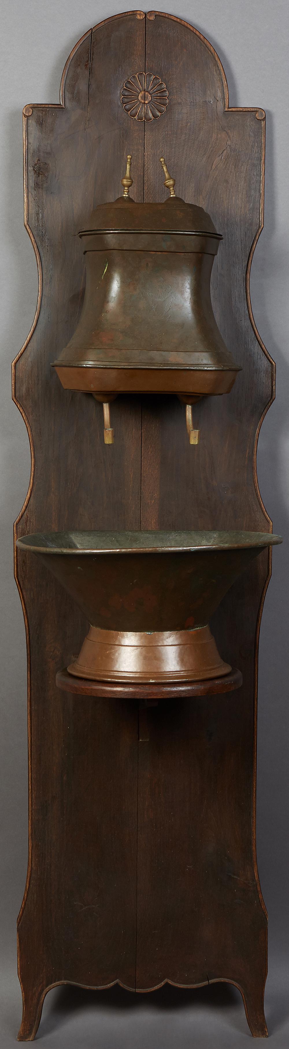 French Provincial Brass and Copper Lavabo, 19th c.,: French Provincial Brass and Copper Lavabo, 19th c., with a copper reservoir over a copper basin, on a carved oak shaped backplate, H.- 80 in., W.- 19 1/2 in., D.- 18 in.