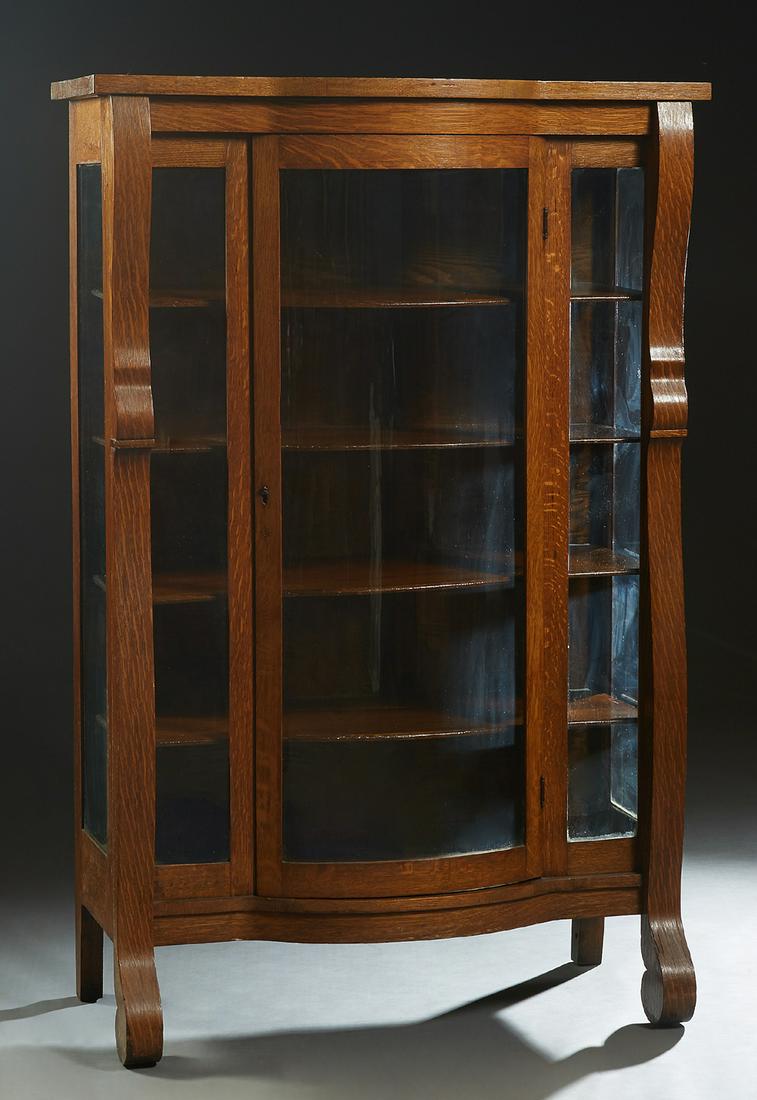 American Carved Oak Curved Glass Curio Cabinet, early: American Carved Oak Curved Glass Curio Cabinet, early 20th c., the bowfront top over a central curved glass door flanked by glass panels and curved glass sides and scrolled pilasters on large scrolled