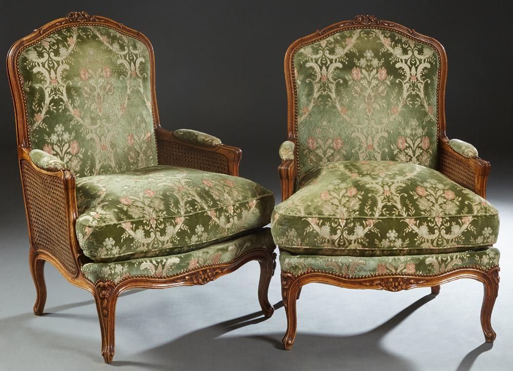 Pair of French Louis XV Style Carved Beech Fauteuils,: Pair of French Louis XV Style Carved Beech Fauteuils, 20th c., the arched floral carved crest rail to an upholstered back, over upholstered double caned arms, to a removable bow front cushion, on scro