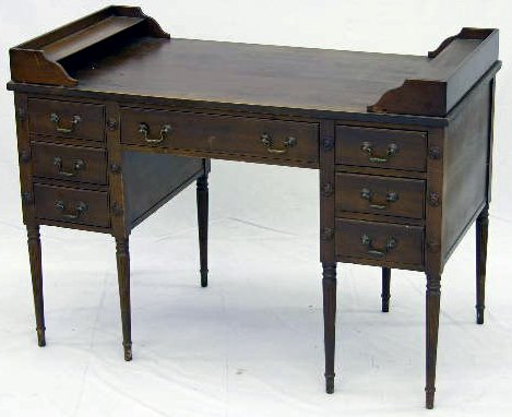 Carved Mahogany Kneehole Desk, c. 1940, the stop w: Carved Mahogany Kneehole Desk, c. 1940, the stop with stepped shelves on both sides, on a base with a single frieze drawer flanked by three small drawers, the whole on reeded legs, H.- 32 in., W.- 44 