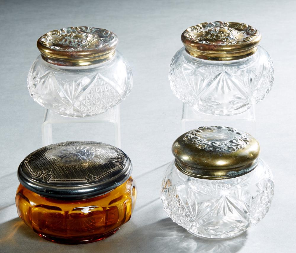 Group of Four Metal and Crystal Dresser Jars, early: Group of Four Metal and Crystal Dresser Jars, early 20th c., two with repousse figural and floral decorated tops, one with repousse floral decorated top, and an amber colored example with an engraved