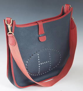 Hermes Evelyne Bicolor PM Shoulder Bag, c. 1995, in red: Hermes Evelyne Bicolor PM Shoulder Bag, c. 1995, in red and navy blue buffalo calf leather with gold hardware, the snap button closure opening to a navy blue suede interior, the exterior of the bag wi