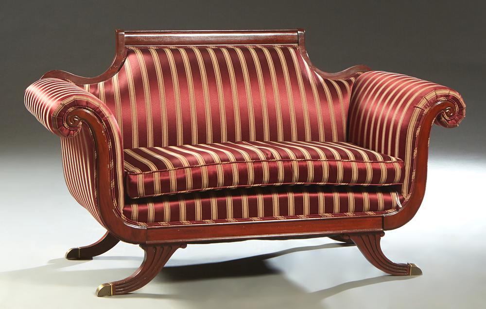 Duncan Phyfe Style Carved Mahogany Settee, 20th c., the: Duncan Phyfe Style Carved Mahogany Settee, 20th c., the canted back with an arched crest rail, to large rolled arms, over a removable seat cushion, on splayed reeded curved legs with brass cap casters