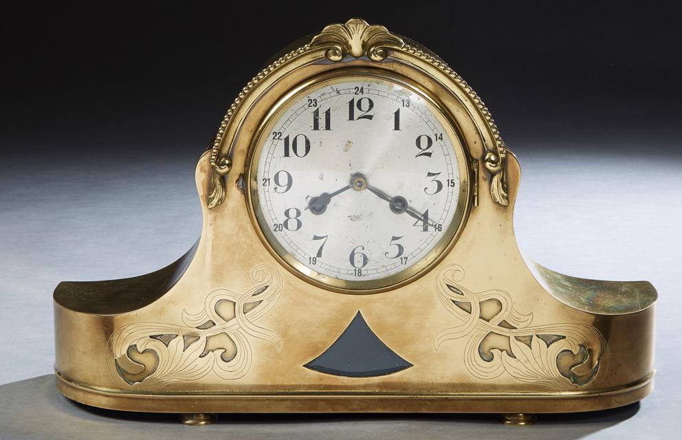 Brass Napoleon Hat Mantel Clock, late 19th c., the: Brass Napoleon Hat Mantel Clock, late 19th c., the arched top over a steel dial time and strike drum clock, above a beveled glass triangular insert, flanked by incised decoration, on three disc feet,