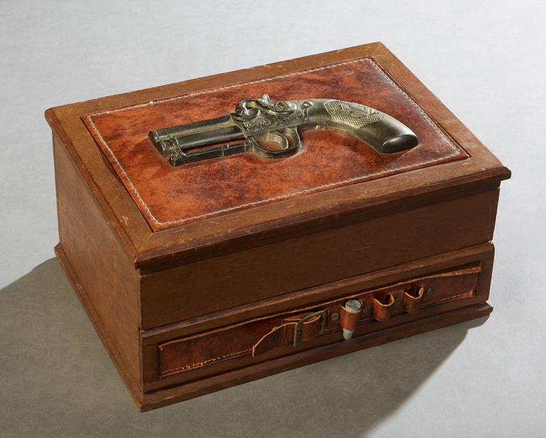 Carved Mahogany Gambler's Box, 20th c., the lid mounted: Carved Mahogany Gambler's Box, 20th c., the lid mounted with a relief pistol, opening to a fitted interior with a roulette wheel, dice, gambling chips, and a lower drawer with a folding green felt gam