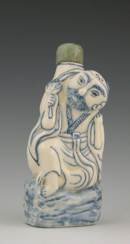 Molded Porcelain Blue and White Snuff Bottle, 1970: Molded Porcelain Blue and White Snuff Bottle, 1970, of a man with a jar on his back, with a jadeite stopper, from the first exhibition of the snuff bottle societyH.- 2 7/8 in., W.- 1 1/4 in., D.- 7/8