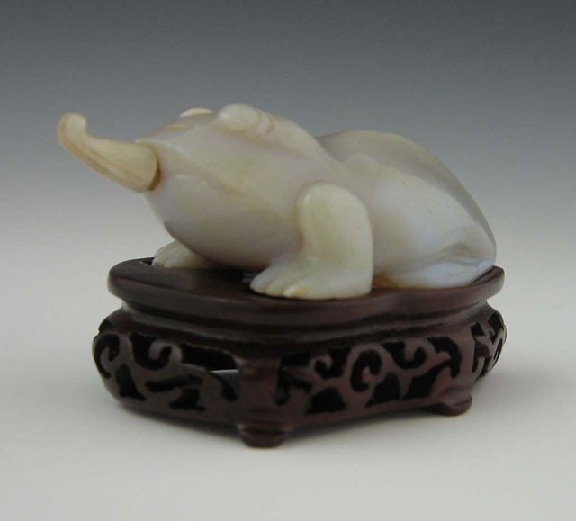 Carved Agate Frog Form Snuff Bottle, early 20th c.: Carved Agate Frog Form Snuff Bottle, early 20th c., the stopper modeled as his tongue, with a custom Carved mahogany base, H.- 1 7/8 in., W.- 2 5/8 in., D.- 1 1/2 in. Provenance: Collection of Virgini