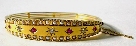 14K Yellow Gold Bangle Bracelet, late 19th c., the: 14K Yellow Gold Bangle Bracelet, late 19th c., the tapered front mounted with five rubies, separated by three diamonds, within a border of seed pearls on both edges, verso with a split band, H.- 1/2 i