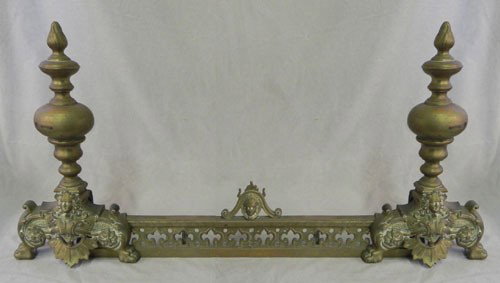 Three Piece Louis XV Style Bronze Chenet Set, 19th: Three Piece Louis XV Style Bronze Chenet Set, 19th c., consisting of a pair of andirons with flame finials atop balls, over central relief male heads, joined by a fender with pierced trefoil decoratio
